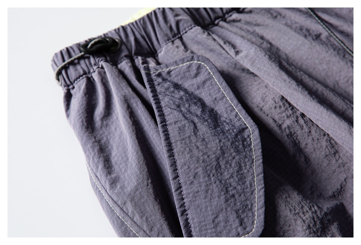 Close-up of a charcoal-gray pants pocket flap with contrast stitching and a textured grid fabric surface.