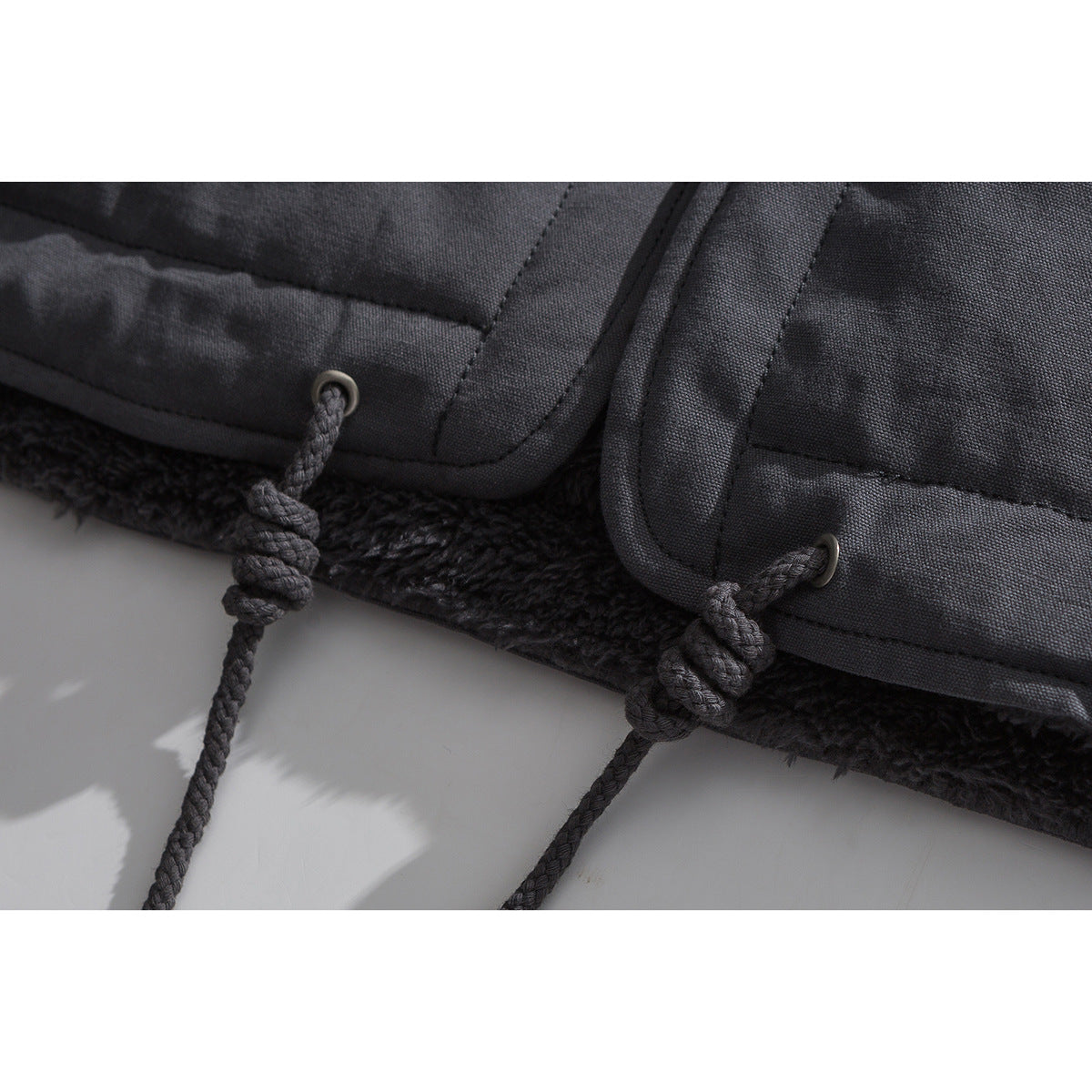 Close-up of a charcoal coat hem with cord loops and plush dark lining.