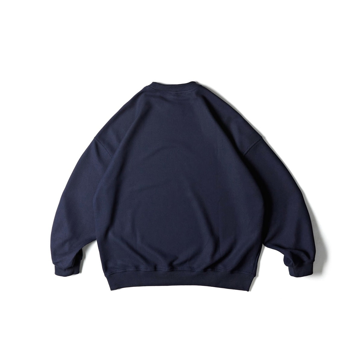 Back view of a plain navy crewneck sweatshirt with dropped shoulders and ribbed cuffs and hem.