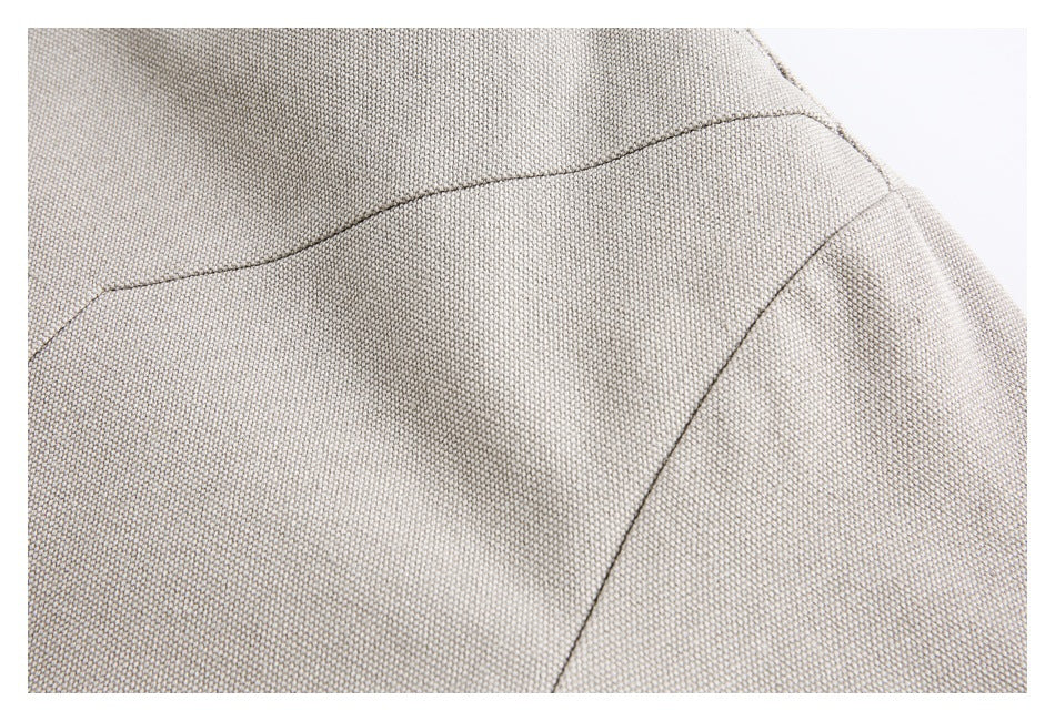 Close-up of the light taupe jacket's textured fabric and curved stitched seams.