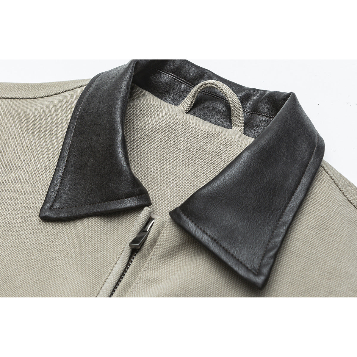 Close-up of a beige textured jacket with a black contrasting collar, loop detail, and front zipper.