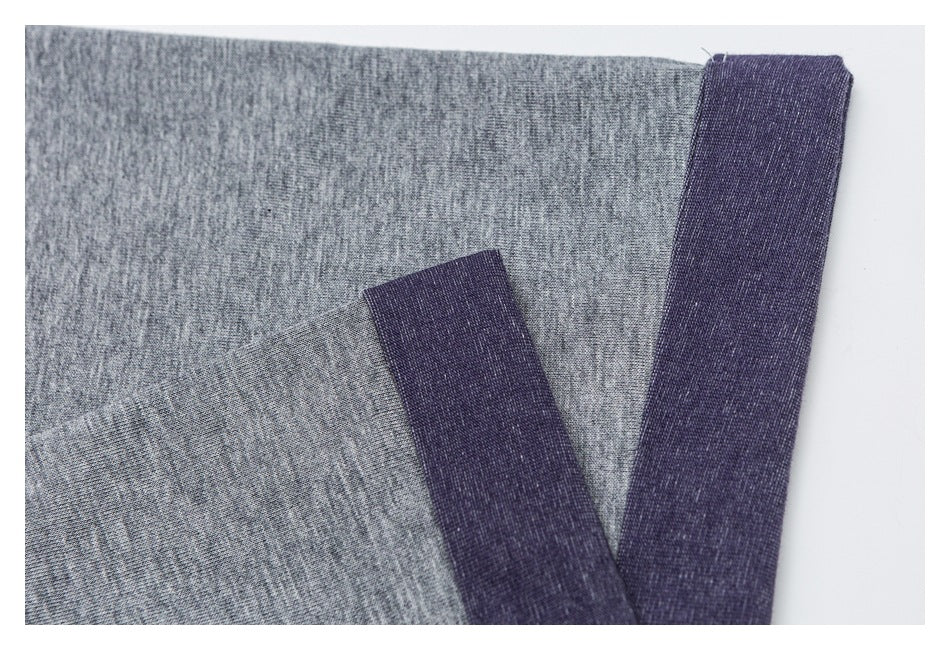 Close-up of heather-gray shirt fabric and dark purple finished edges.