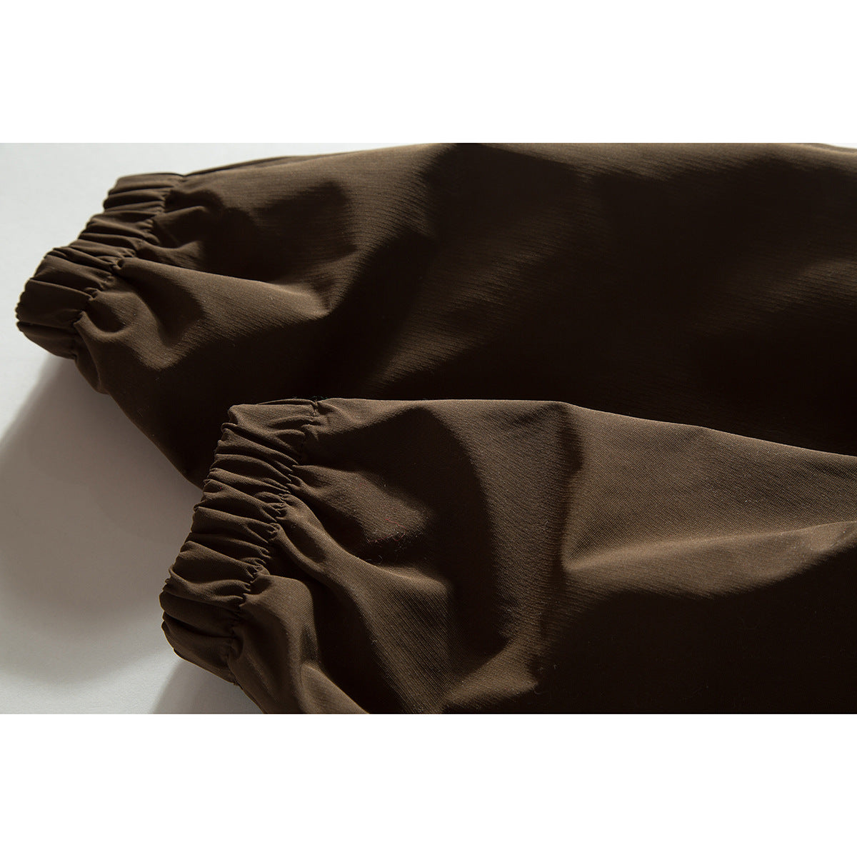 Close-up of gathered elastic cuffs on brown jacket sleeves.