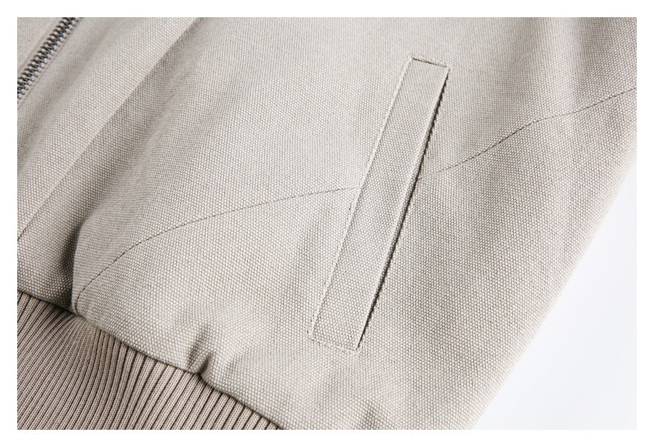 Close-up of the jacket's slanted welt pocket, textured fabric, and ribbed lower edge.