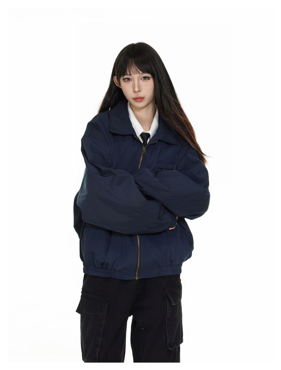 Closer front view of a model wearing a zipped navy jacket with a white shirt and black tie.