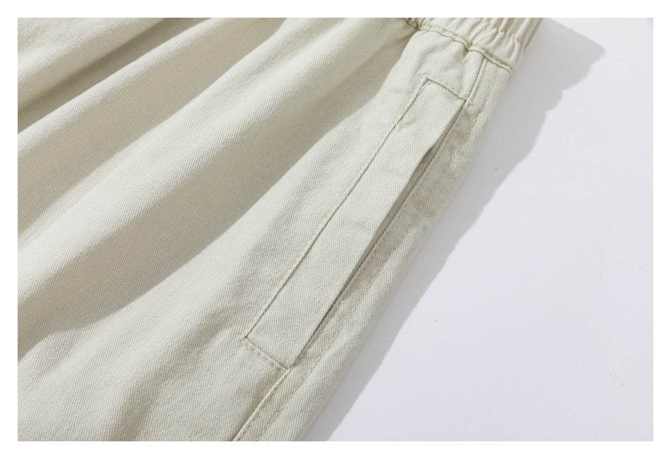 Close-up of a long side pocket and stitching on light beige trousers.