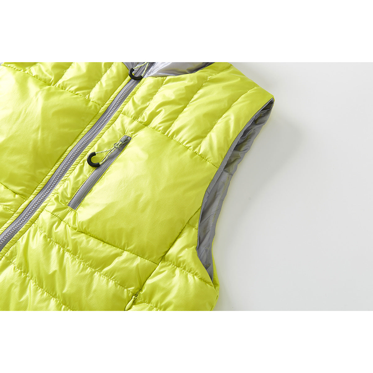 Angled close-up of the lime-yellow quilted vest, showing its chest pocket, front zipper, and gray armhole lining.