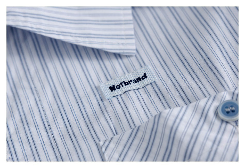 Close-up of a small sewn brand label on white fabric with fine blue stripes.