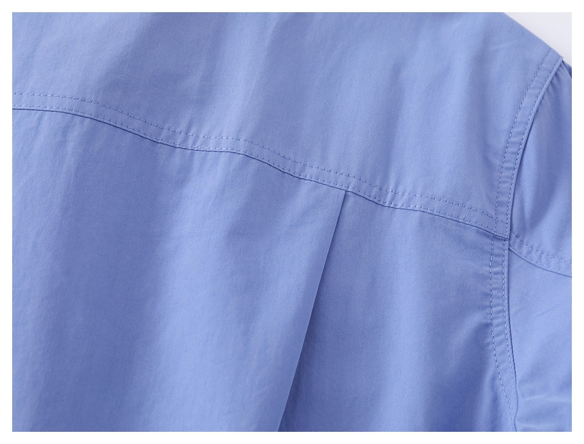 Close-up of the stitched back yoke and shoulder seam on a light blue shirt.