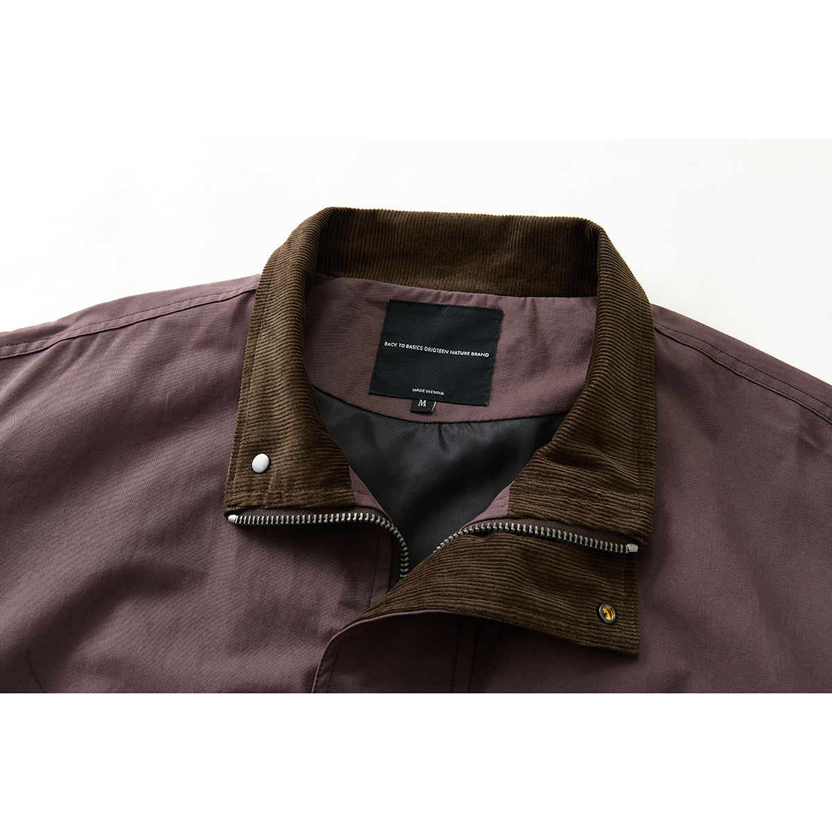 Close-up of a plum jacket's brown corduroy collar, zipper, lining, and sewn neck label.