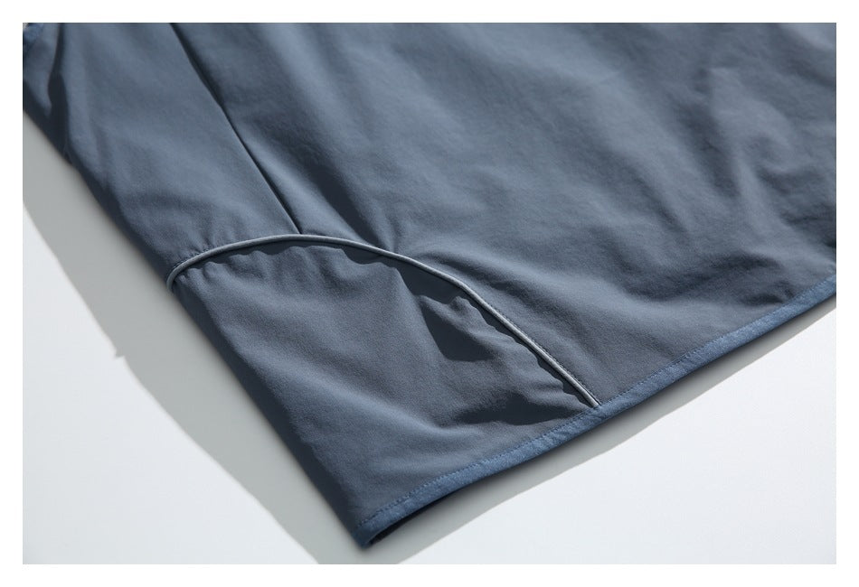 Close-up of a curved seam and bound hem on a blue-gray garment.