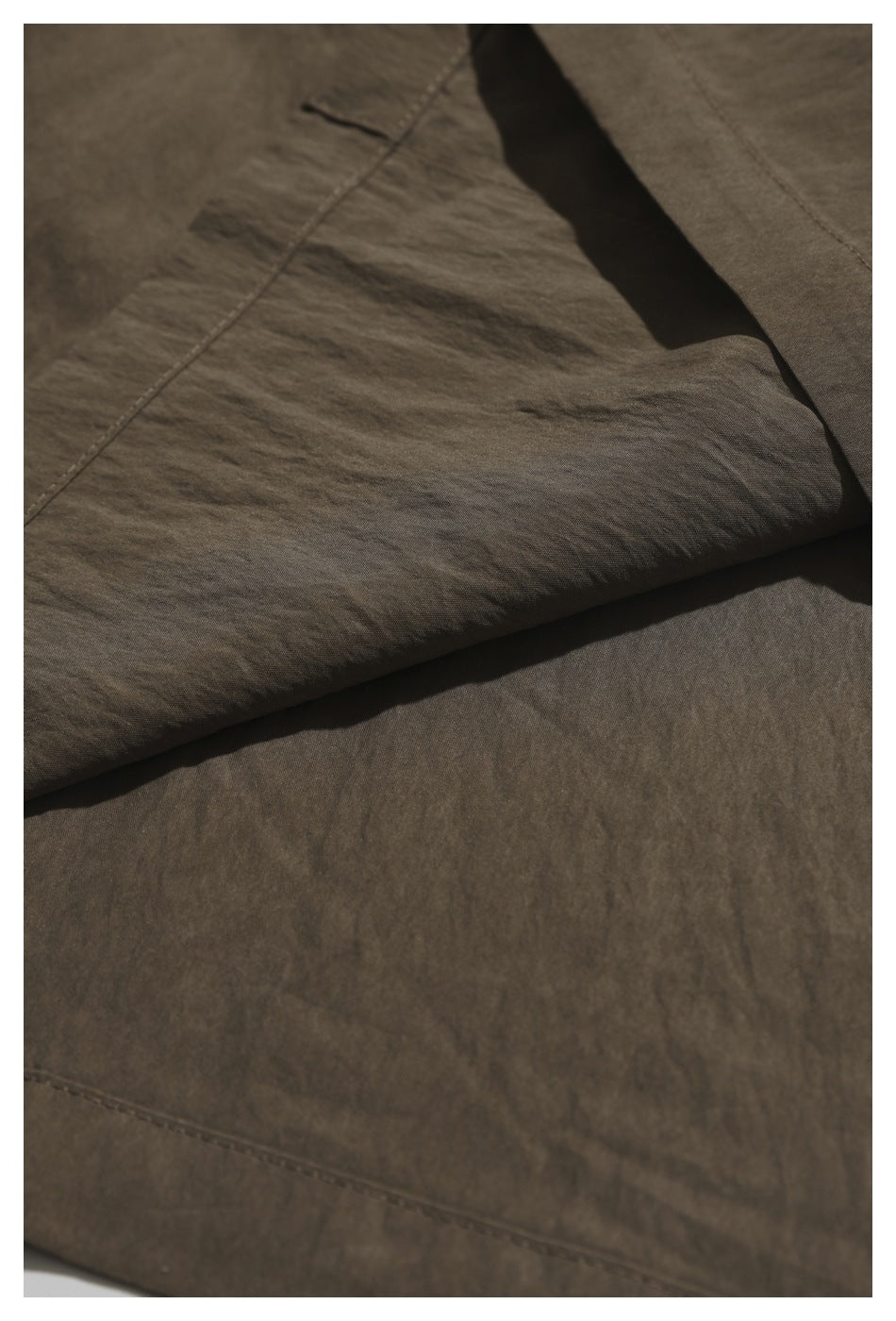Close-up of the brown shirt fabric folded over to show its texture and stitching.