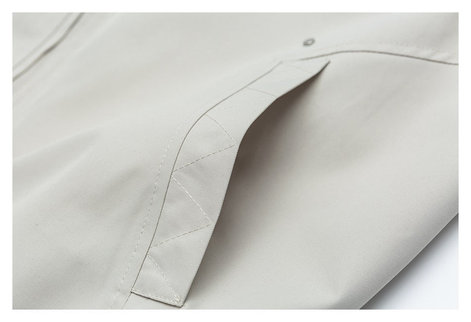 Close-up of a light gray jacket pocket flap with triangular stitch details.