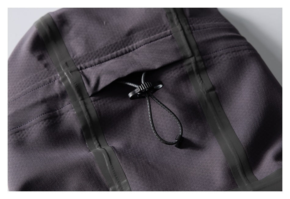 Close-up of a black drawcord toggle between vertical seam-tape strips on the jacket.
