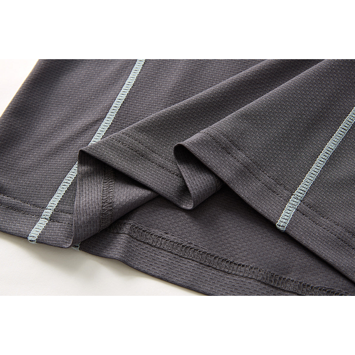 Close-up of charcoal fabric, pale blue contrast seams and a folded hem.