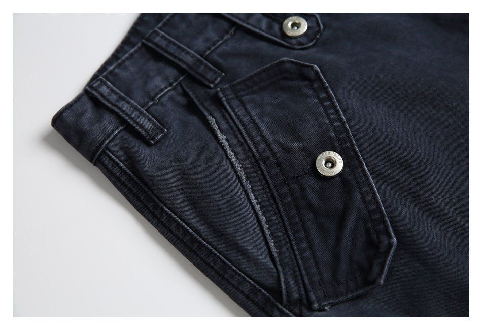 Close-up of a dark charcoal jeans pocket with a buttoned flap and nearby belt loops.