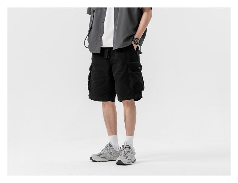 Model wearing black cargo shorts with large flap pockets, shown from the front against a white background.