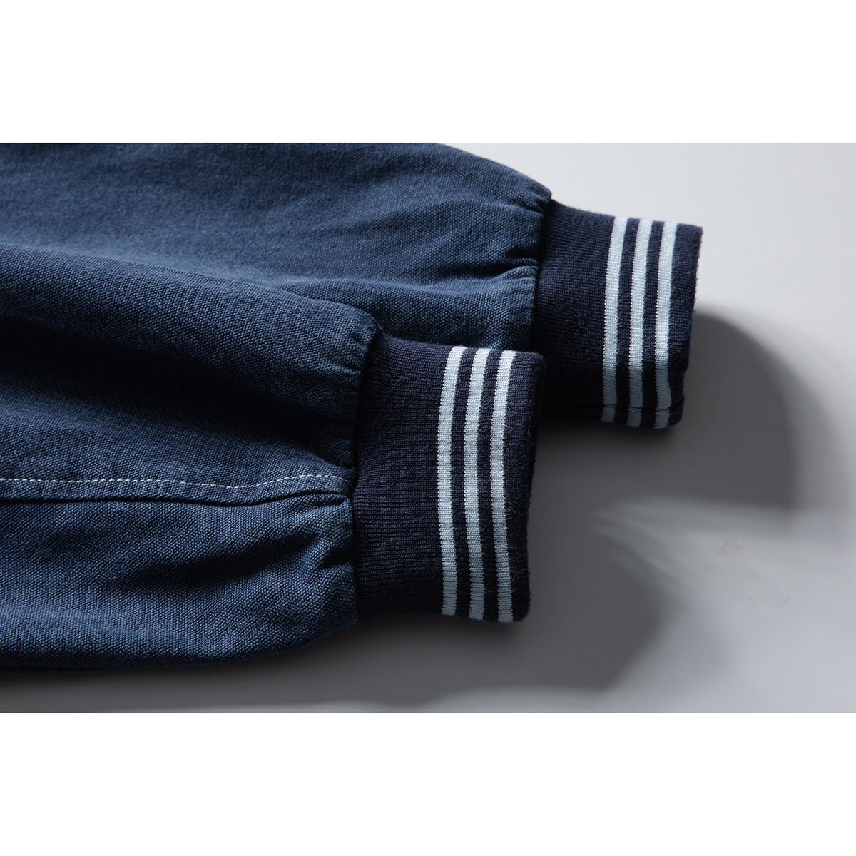Close-up of the navy jacket's sleeves and dark ribbed cuffs with three pale stripes.