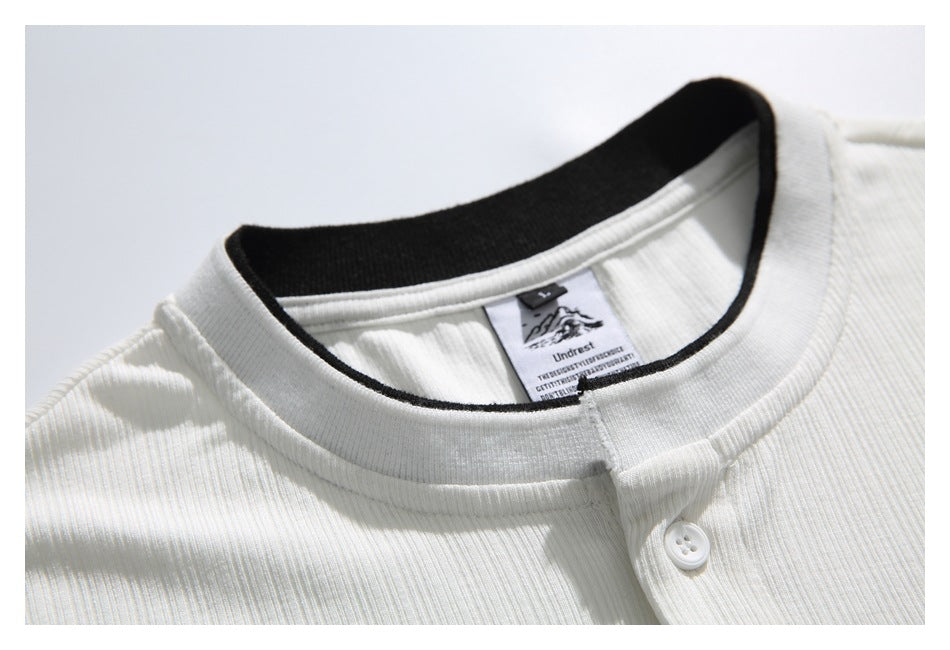Close-up of the white shirt's ribbed collar, black inner neckline trim, sewn label and top button.