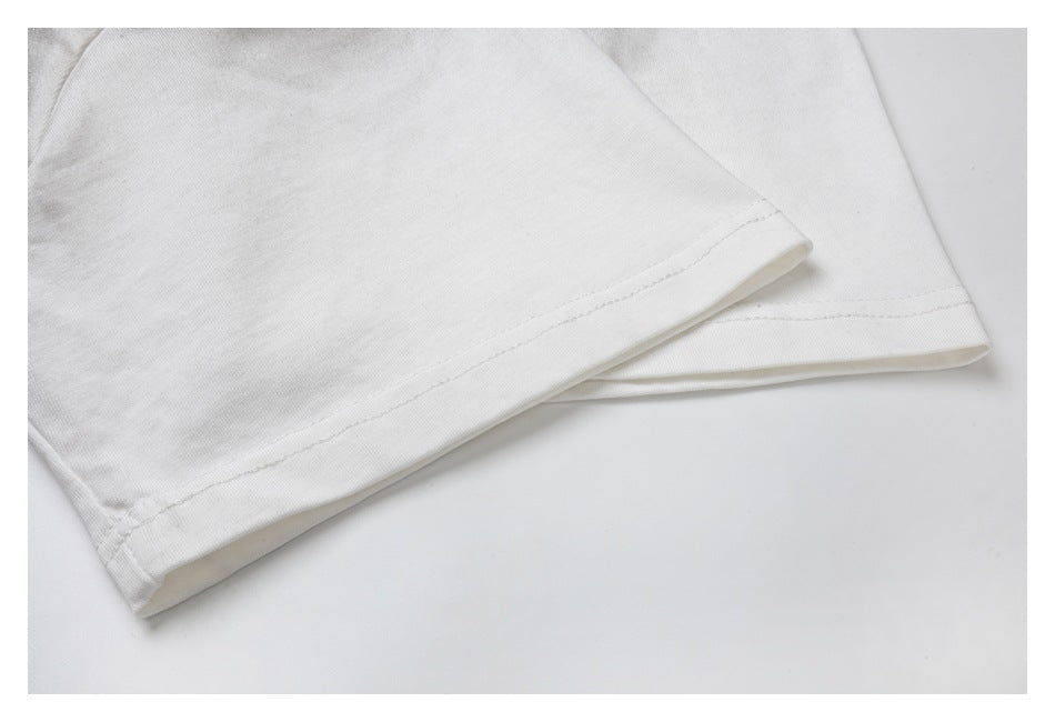 Close-up of the stitched hem on a white garment, with another folded edge behind it.