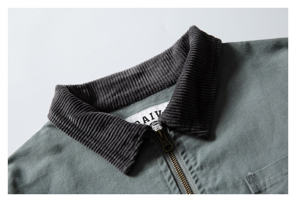 Close-up of a gray-green jacket collar with dark ribbed trim, a brass-colored zipper, and a partially visible inner label.