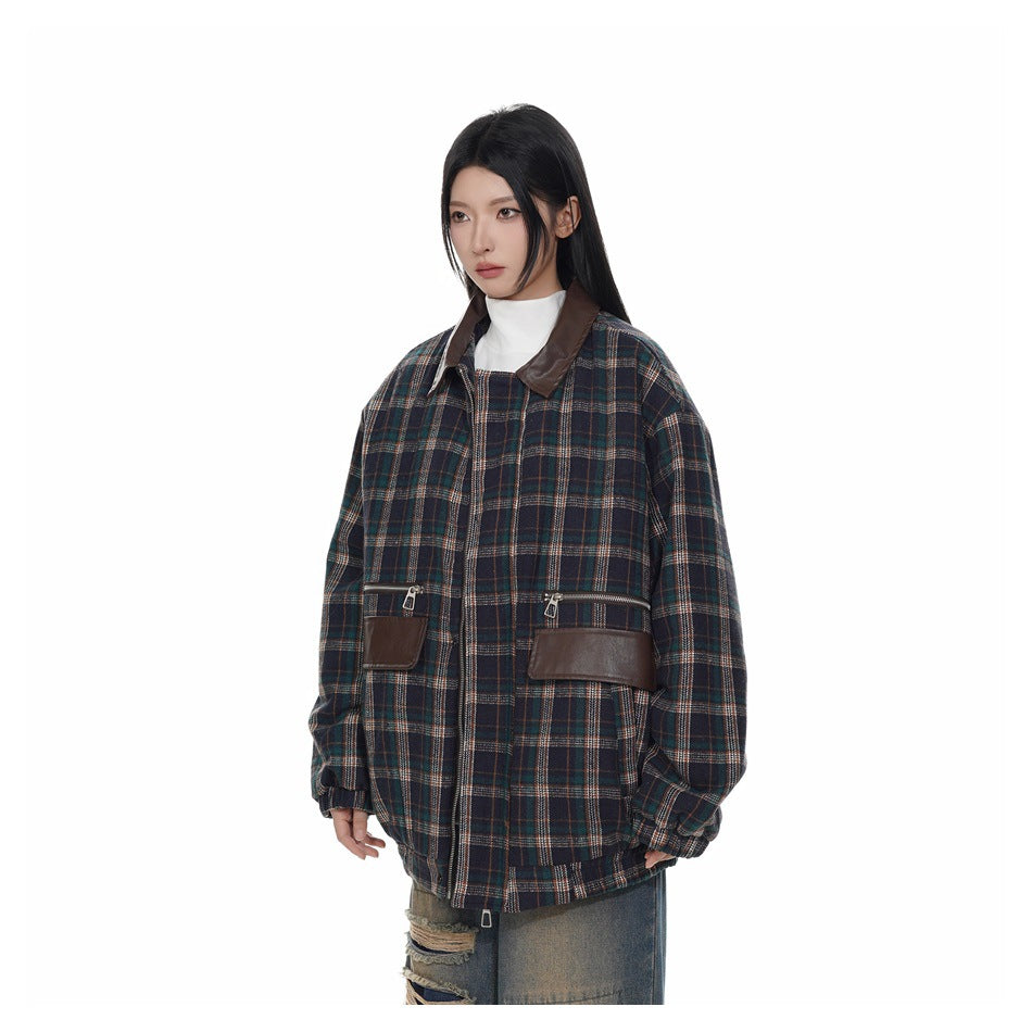 Three-quarter view of a model wearing a dark navy plaid jacket with a brown collar and matching zip pocket flaps.