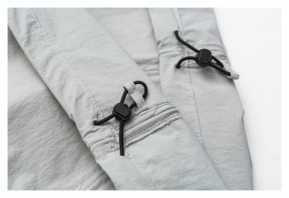 Close-up of light gray pant leg openings with black drawcords and toggle adjusters.