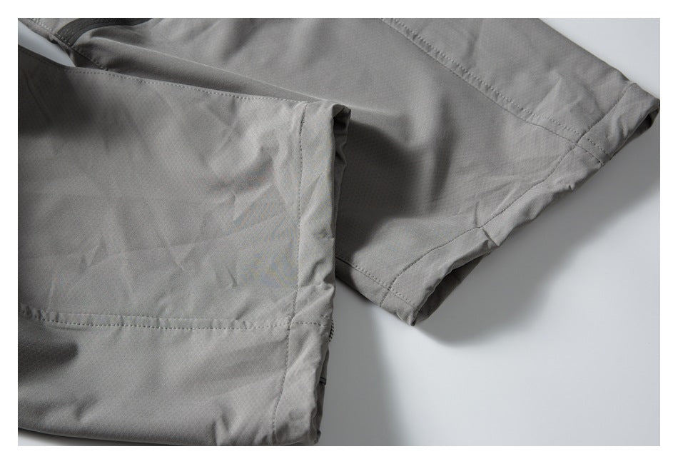 Close-up of gray pants showing stitched leg panels and finished hems.