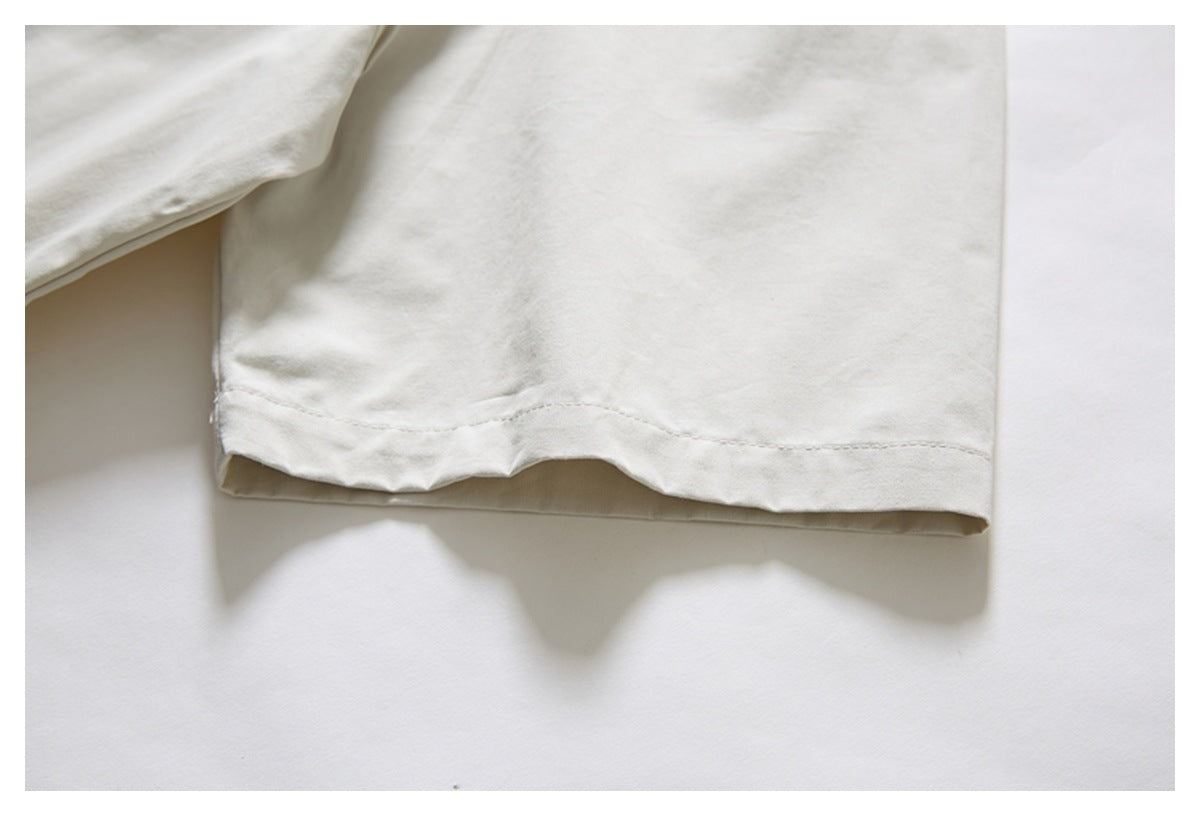 Close-up of an ivory shirt sleeve and its stitched cuff hem.