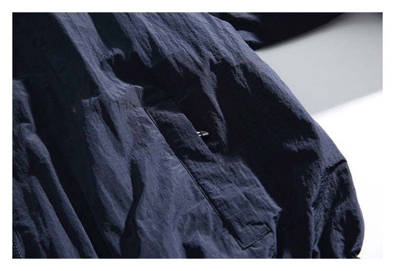 Close-up of a dark navy jacket sleeve and flap pocket with a small snap.