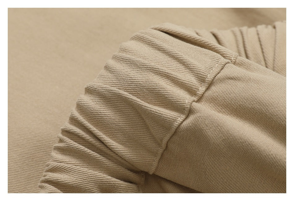 Close-up of the gathered elastic waistband and stitching on beige pants.
