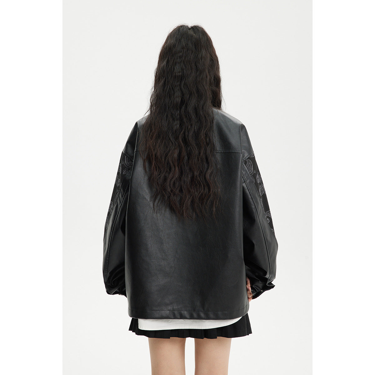Back view of a model wearing an oversized black jacket with paisley-patterned sleeves.