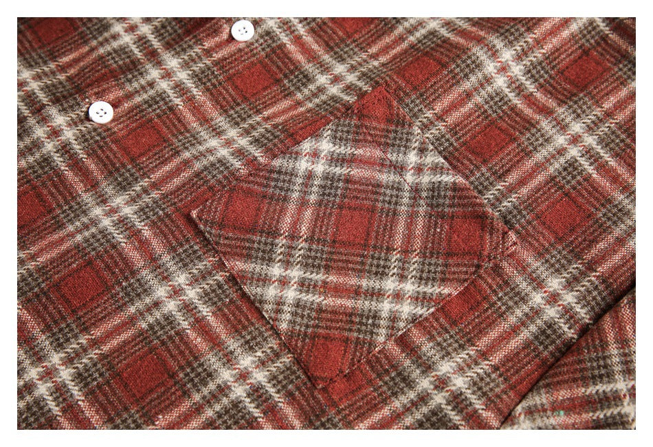 Close-up of a red, brown, and cream plaid shirt showing a chest pocket and white buttons.