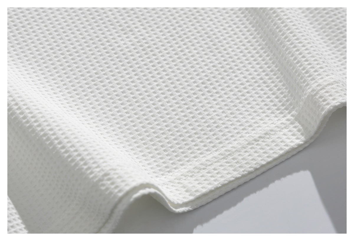 Close-up of white textured fabric draped to show its hem and raised weave.