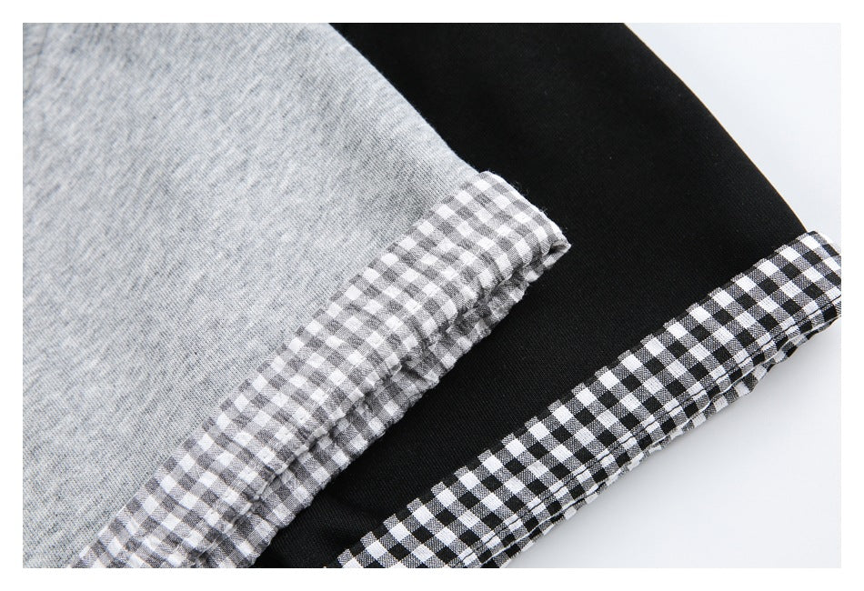 Close-up of gray and black tee sleeves with contrasting gingham cuff trim.