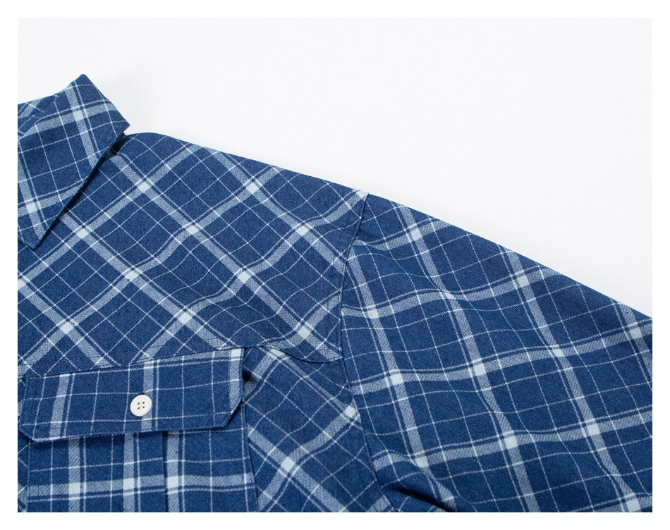 Close-up of a blue-and-white plaid shirt showing the collar, chest pocket, shoulder, and sleeve.