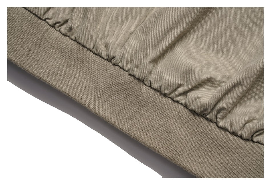 Close-up of a taupe jacket's gathered edge above a wide ribbed knit band.