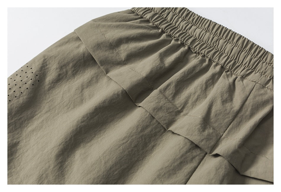 Taupe garment close-up showing a gathered elastic waistband, layered panels, and small black dots.