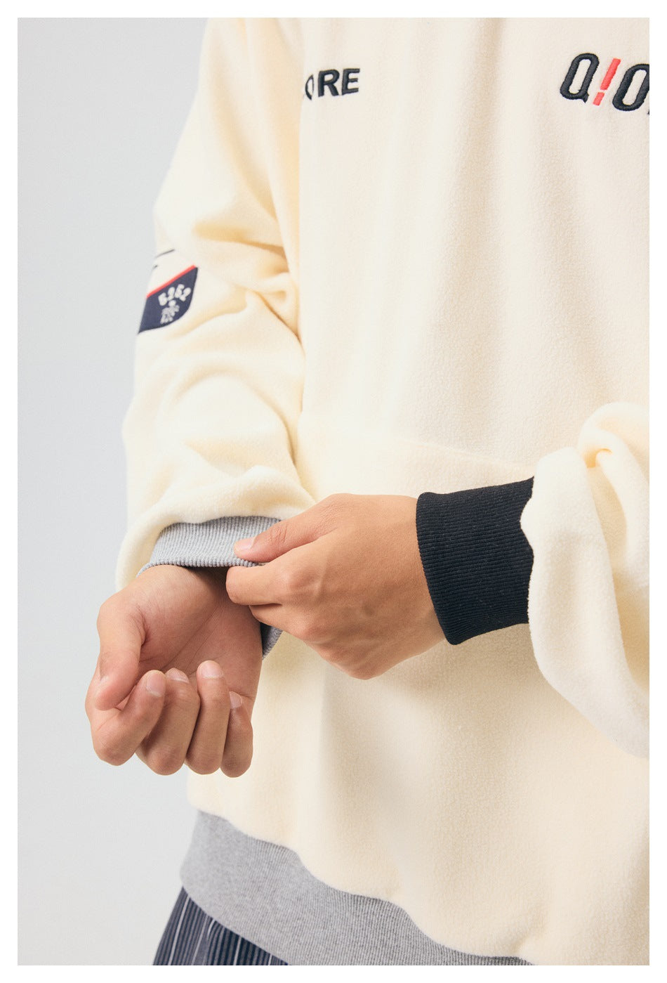 Close-up of the cream pullover's sleeve cuff, showing gray ribbing and a dark inner cuff.