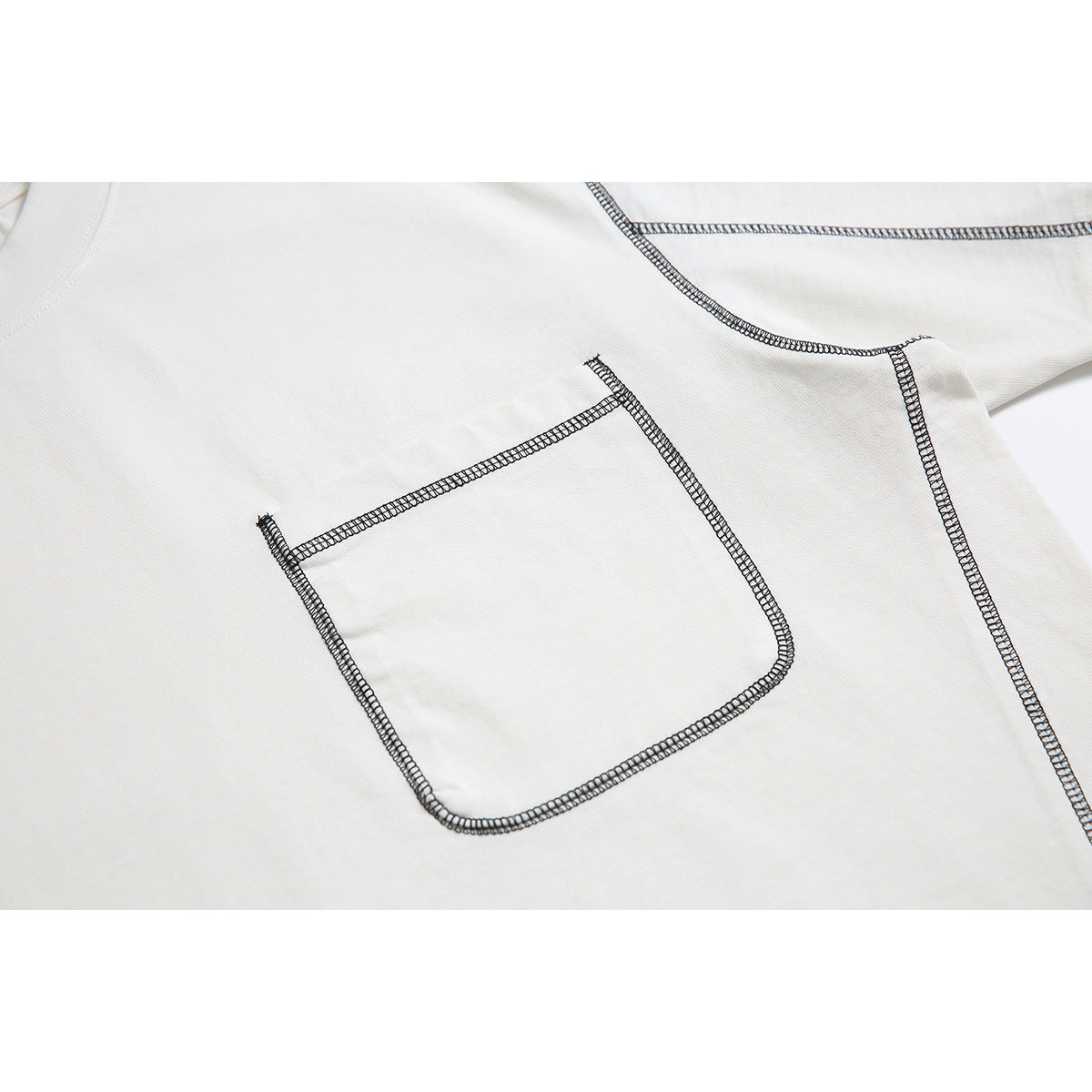 Close-up of the off-white T-shirt's chest pocket and prominent dark contrast stitching.