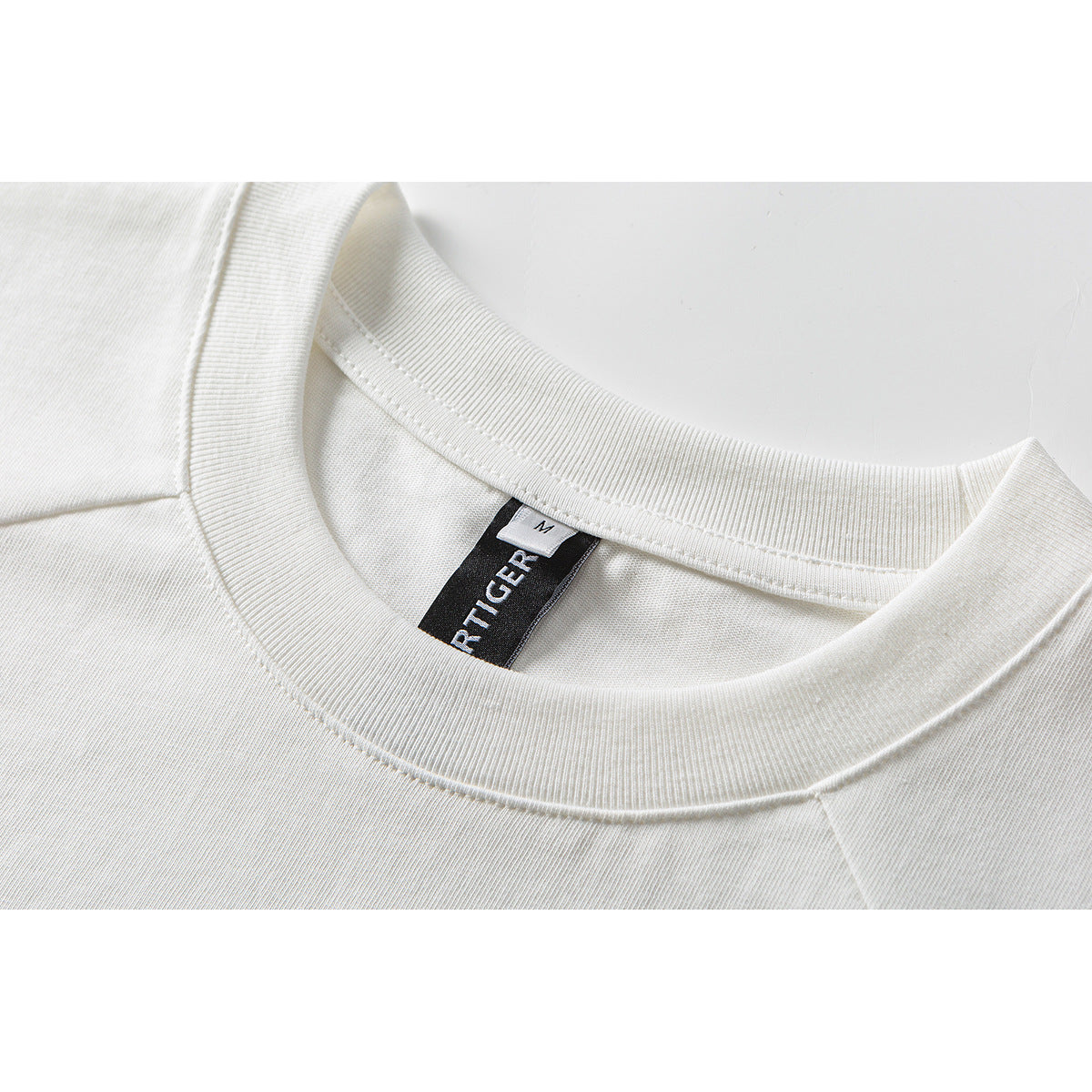 Close-up of a white T-shirt's ribbed crew neckline and inner size label.