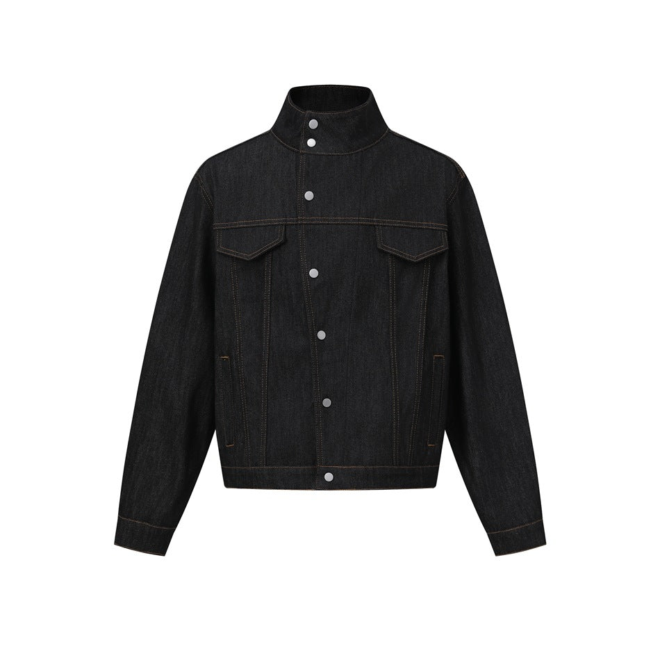 Black denim jacket flat lay front view with stand collar, asymmetric snap placket, chest flap pockets and tan stitching