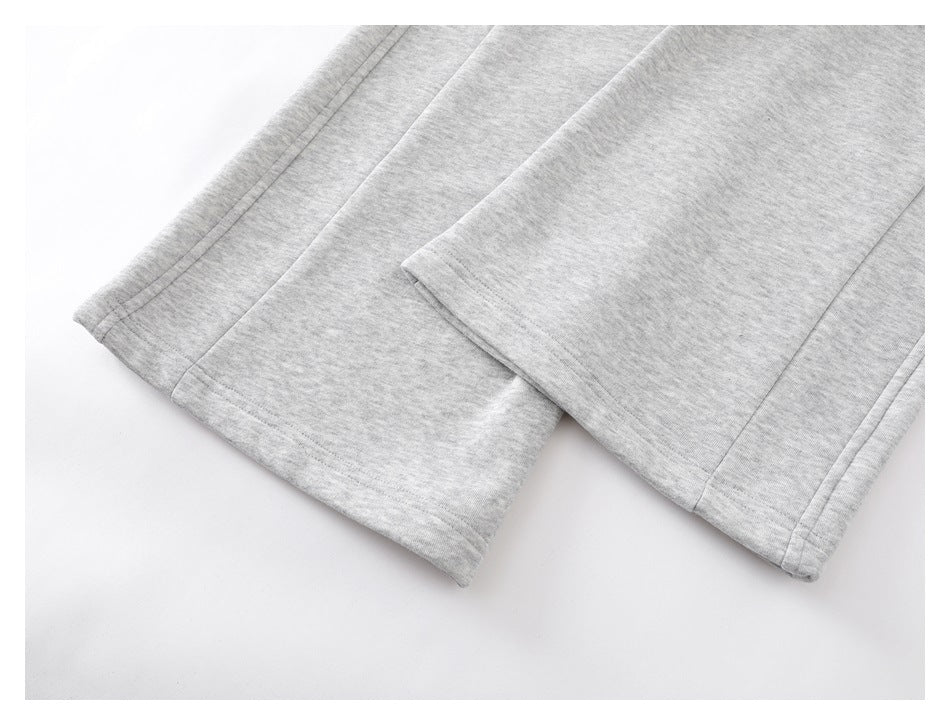 Close-up of the finished hems on light gray sweatpants laid flat.