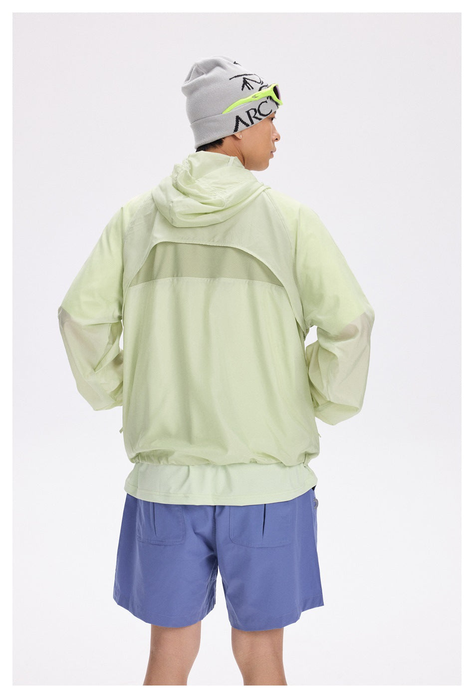 Man modeling the back of a pale lime hooded jacket with a horizontal back panel.