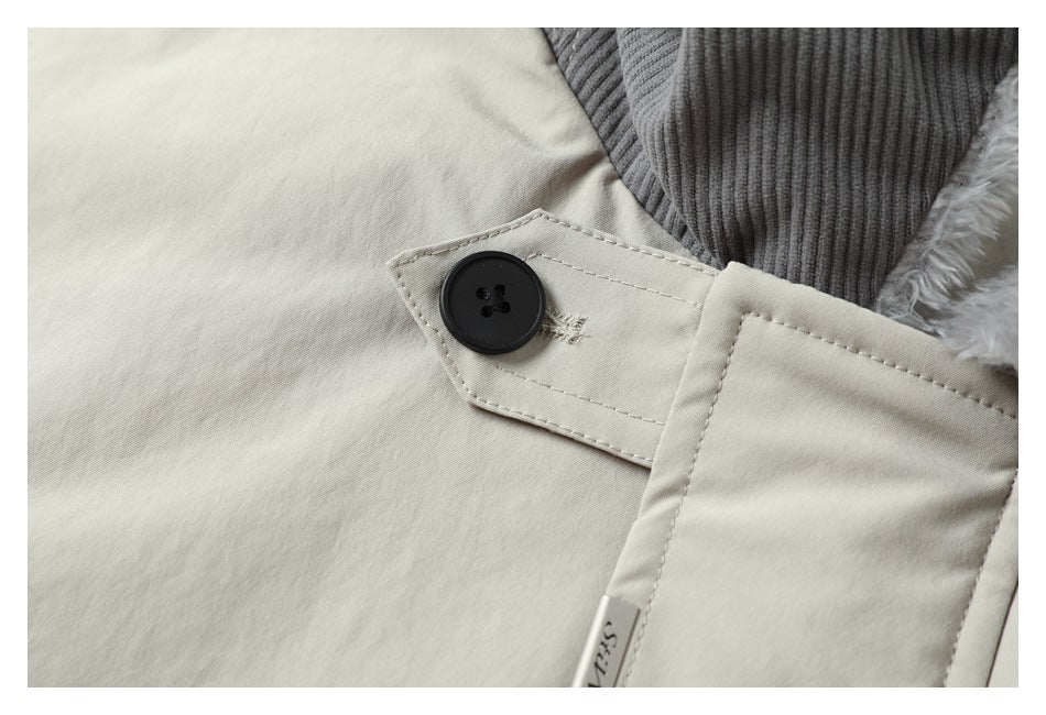 Close-up of a black button and fastening tab on a cream coat beside a gray ribbed collar.