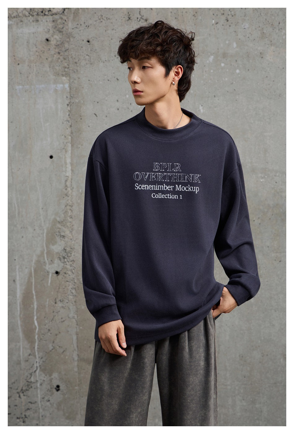 Close view of a man wearing a dark gray long-sleeve sweatshirt with chest lettering and gray pants