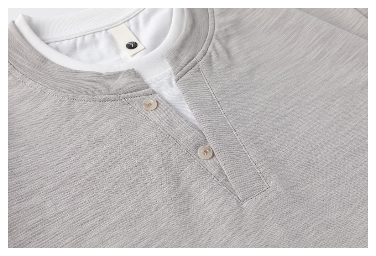 Close-up of the light gray shirt's two-button placket, neckline, and textured knit surface.