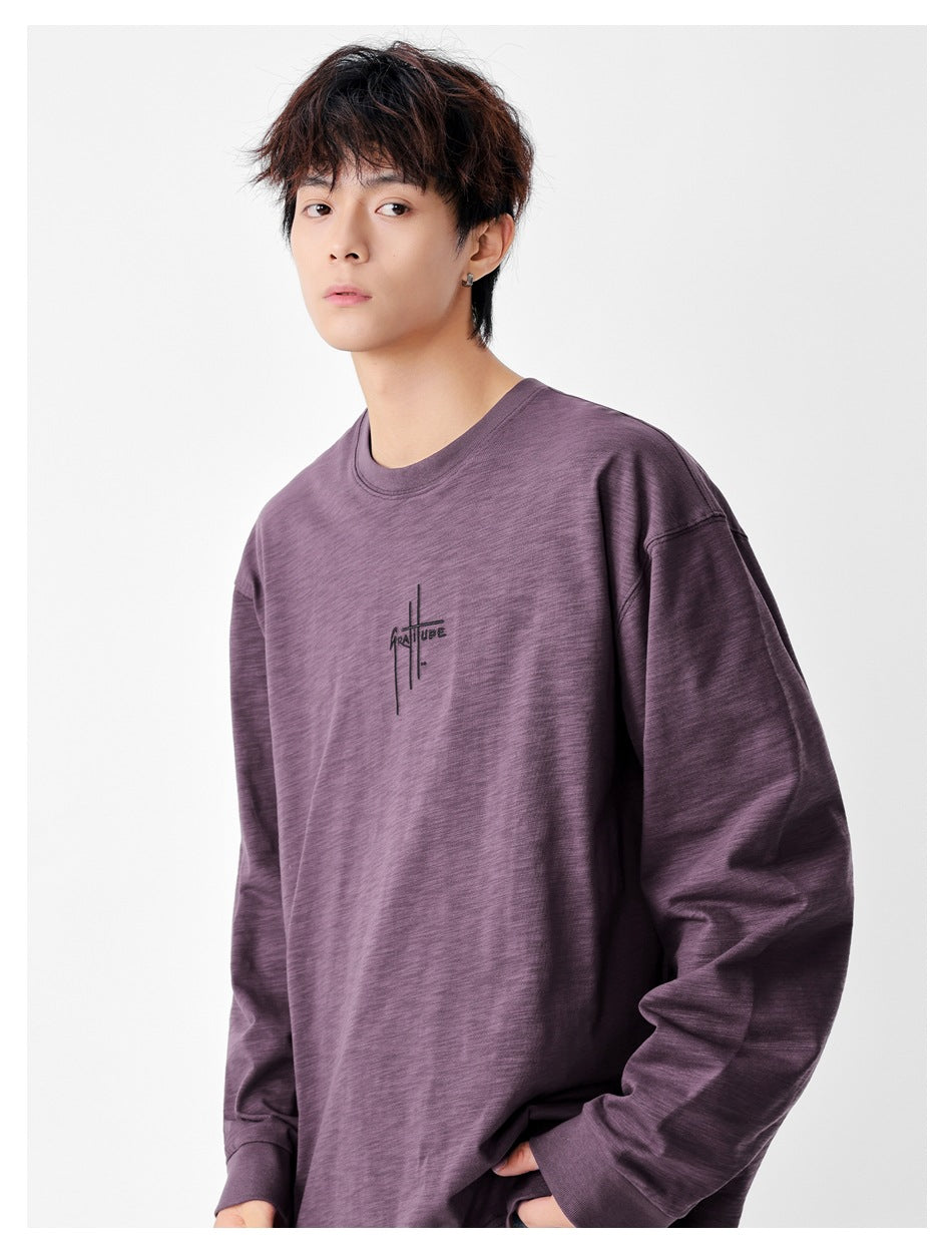 Close view of a model wearing an oversized plum long-sleeve shirt with a small black chest graphic.