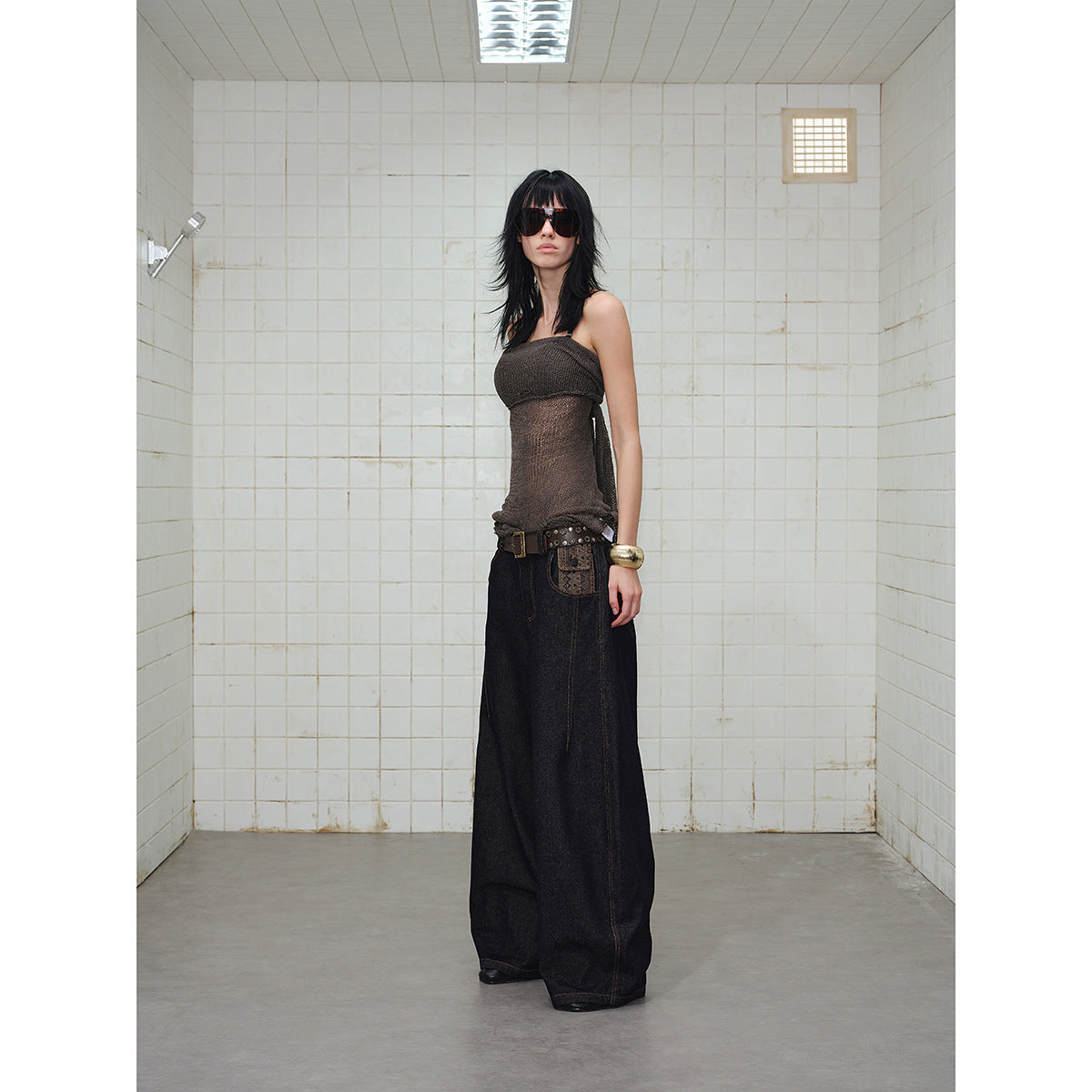 Model wearing dark indigo wide-leg jeans with a patterned pocket detail and a sheer brown sleeveless top.