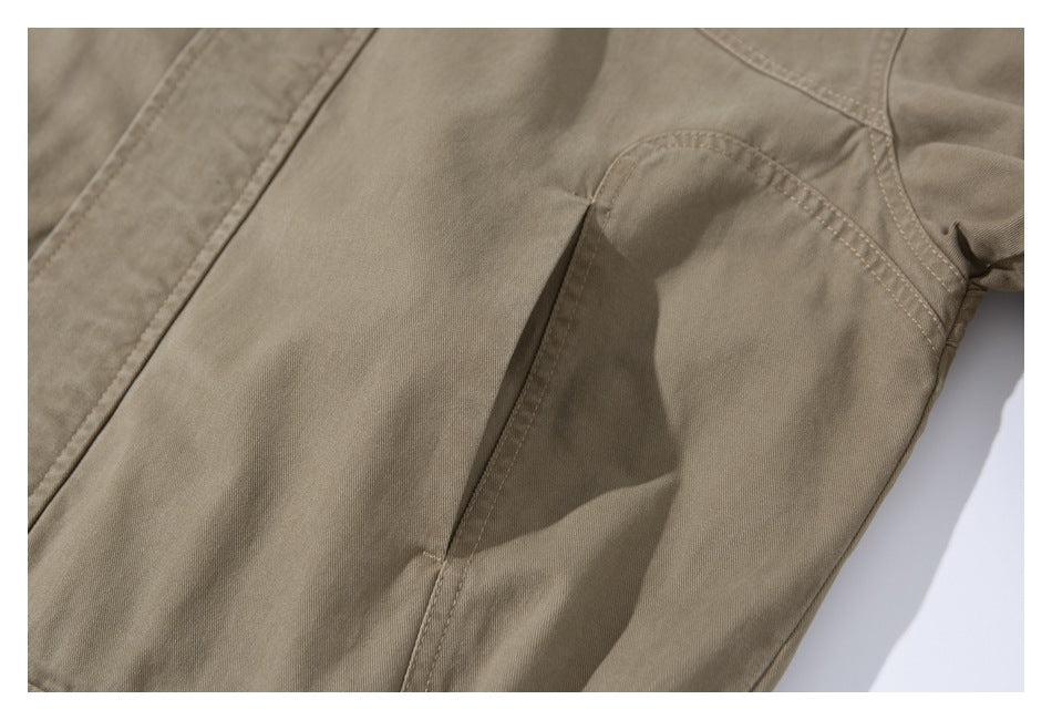 Close-up of a taupe jacket panel showing a vertical pocket opening and curved stitched seam.